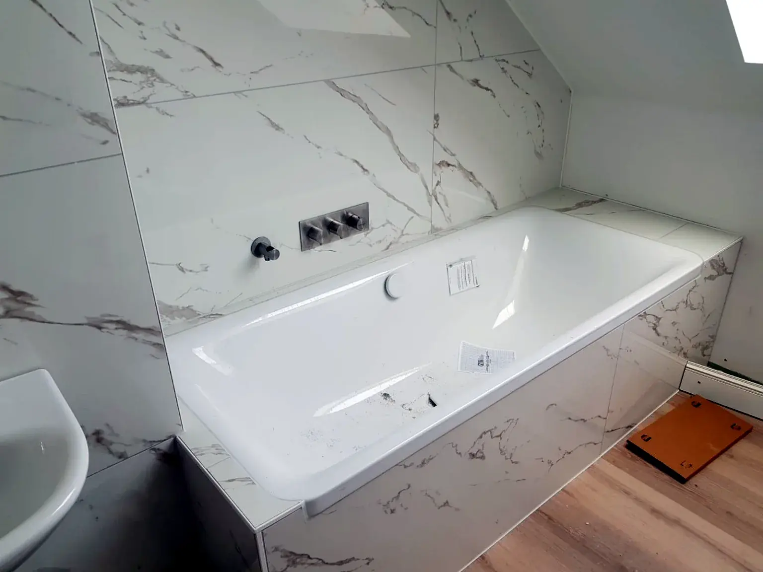 Baignoire encastrée avec habillage et murs effet marbre.