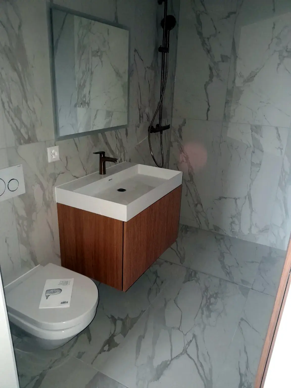 Petit meuble vasque bois dans une salle de bains effet marbre.