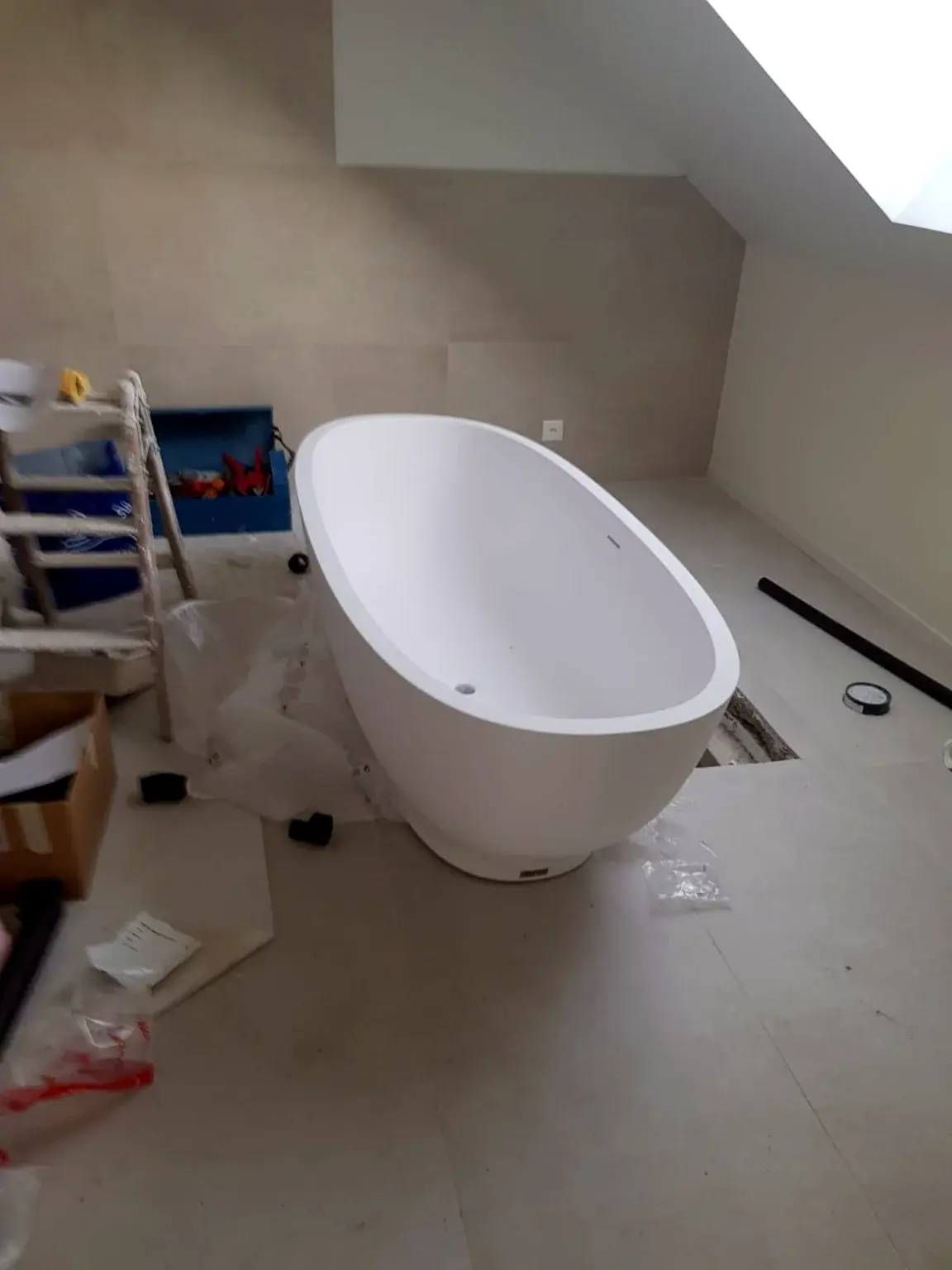 Installation d’une baignoire îlot dans une salle de bains mansardée.