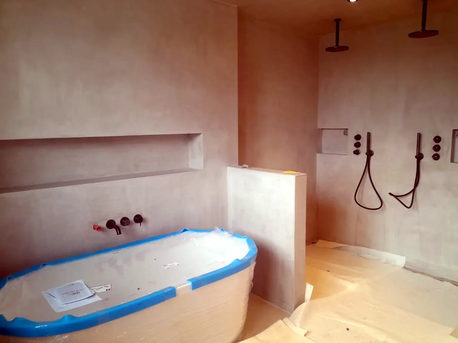 Salle de bains en cours de finition avec baignoire et espace douche.