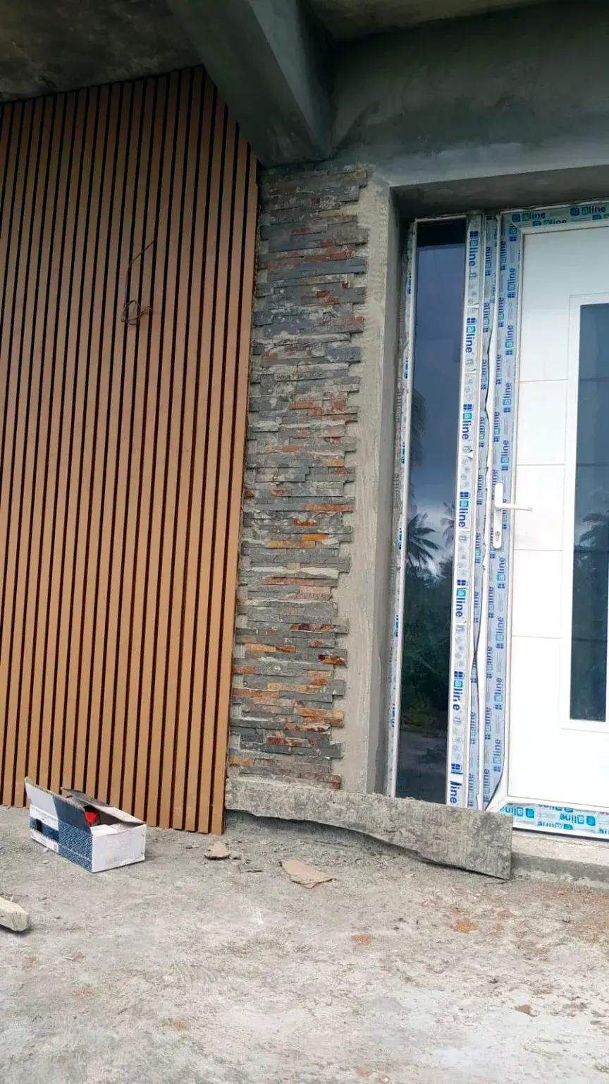 Détail de bardage vertical et parement minéral autour d’une entrée.