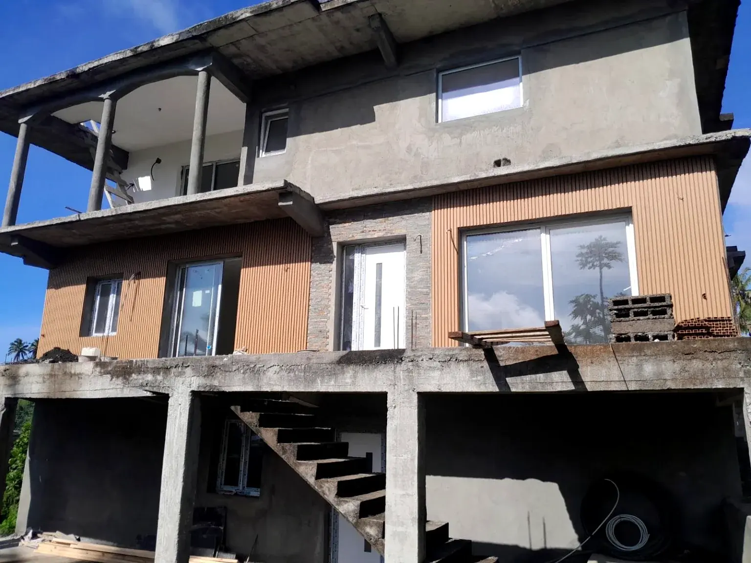 Façade d’une maison en cours de finition avec bardage et ouvertures.