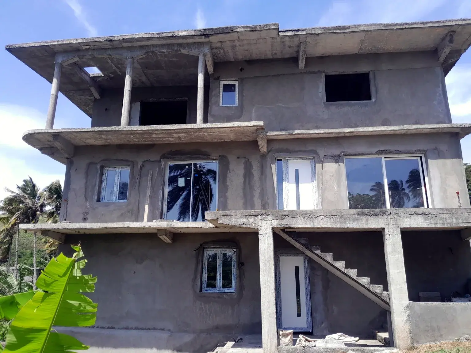 Maison en construction avec menuiseries installées et façades en préparation.