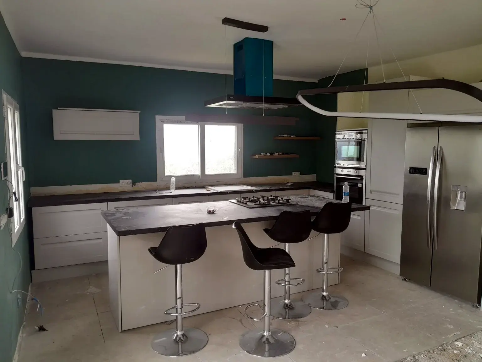 Cuisine contemporaine blanche avec îlot central, plan de travail sombre et électroménager intégré.