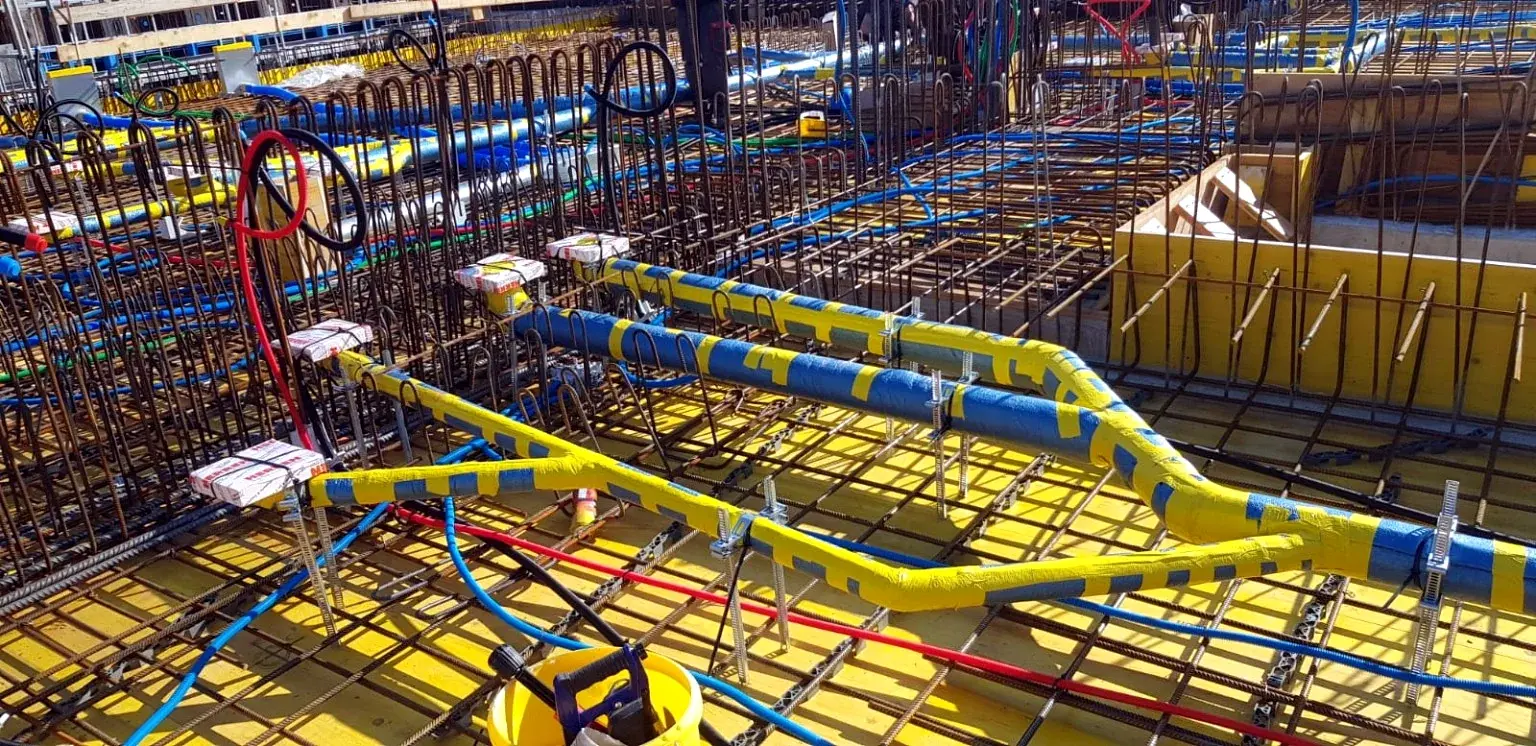 Détail de conduites et gaines techniques fixées sur le ferraillage.