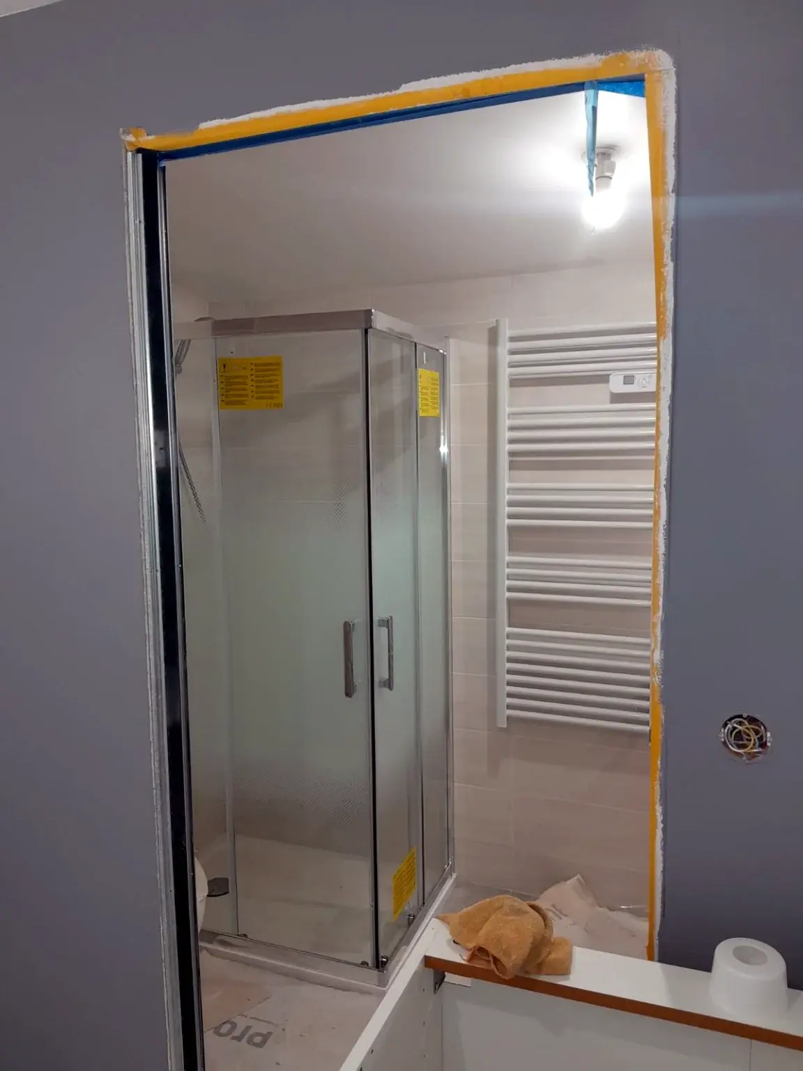 Cabine de douche et sèche-serviettes installés dans une salle de bains en phase finale.