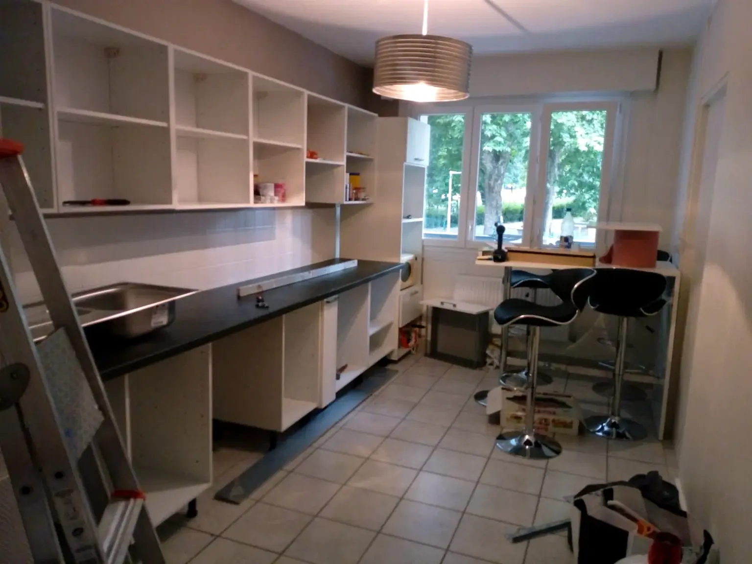 Vue large d’une cuisine blanche en cours de montage.