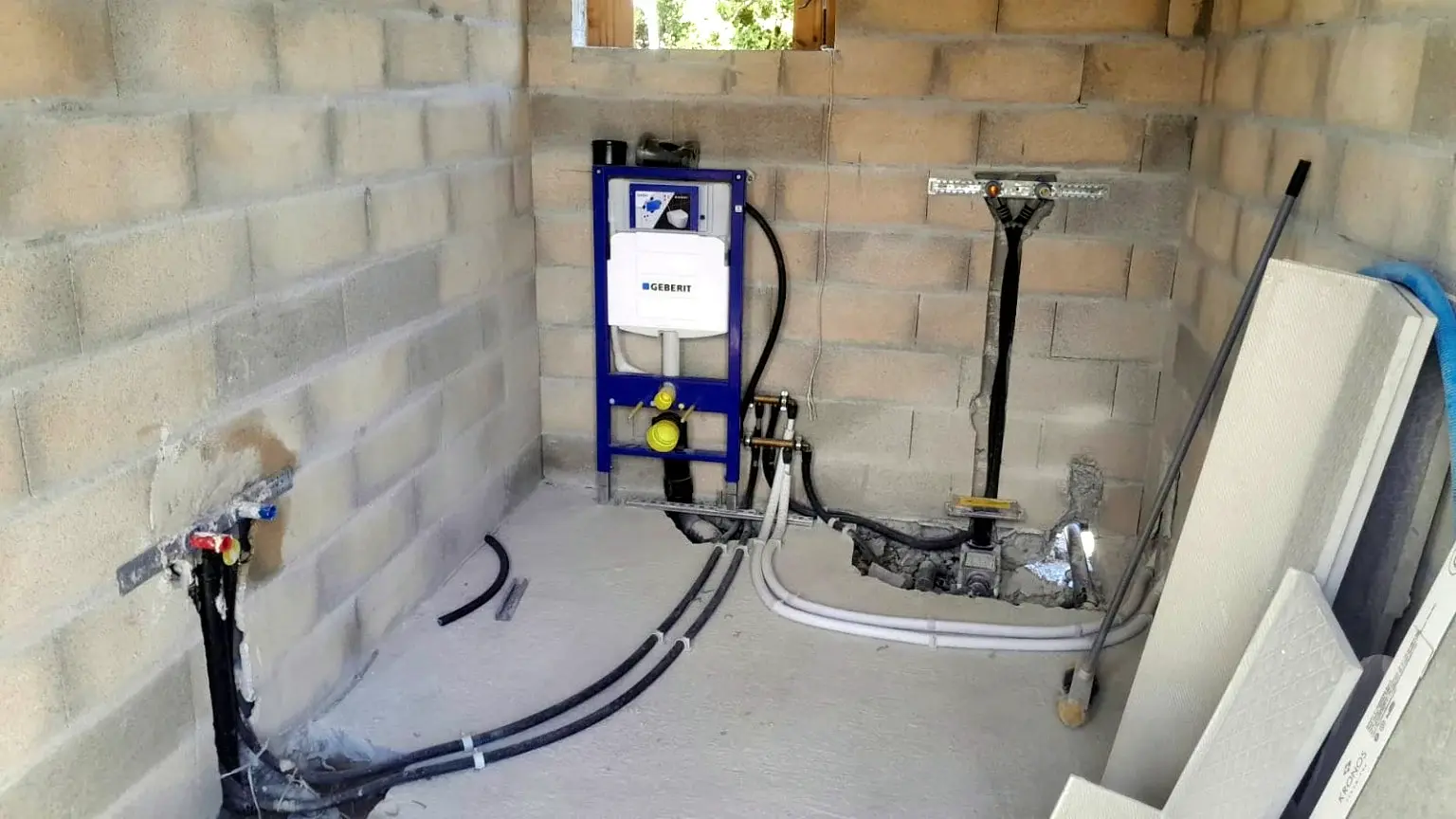 Préparation des réseaux de plomberie et du bâti-support dans une salle de bains en construction.