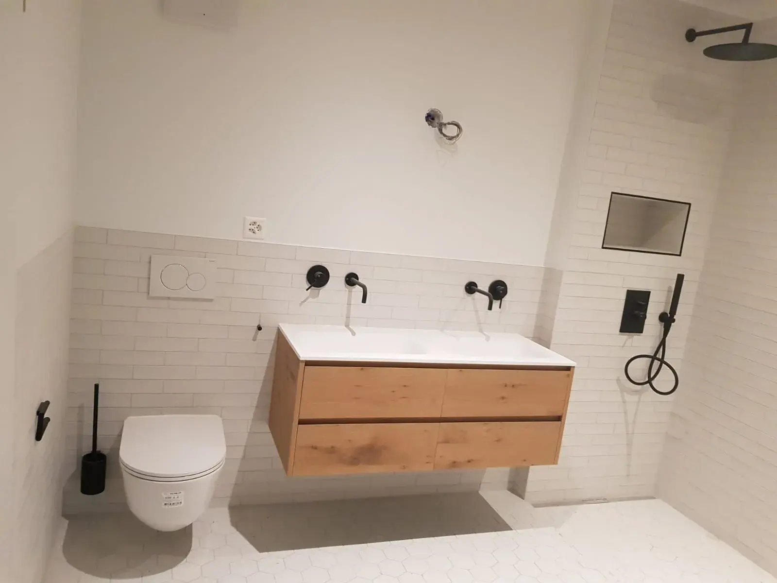 Double vasque en bois clair et WC suspendu, carrelage métro blanc, salle de bain terminée.