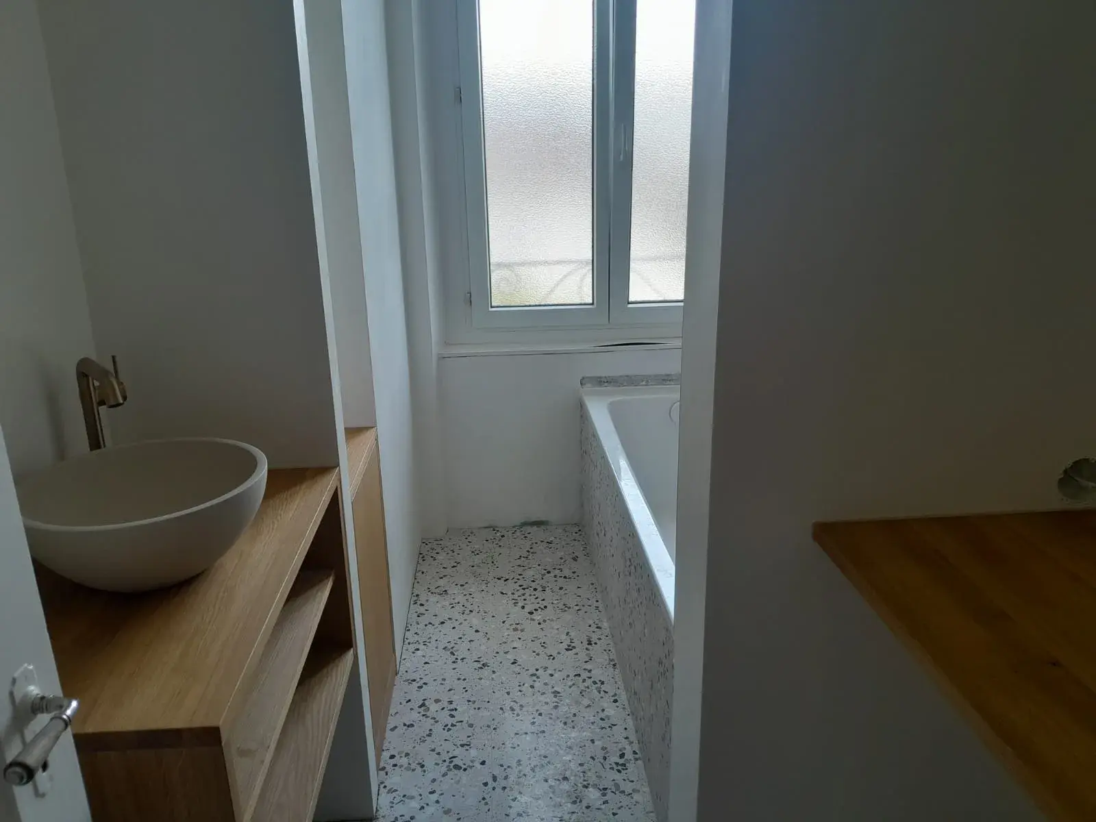 Vasque en pierre ronde sur console en bois clair, salle d’eau terminée.