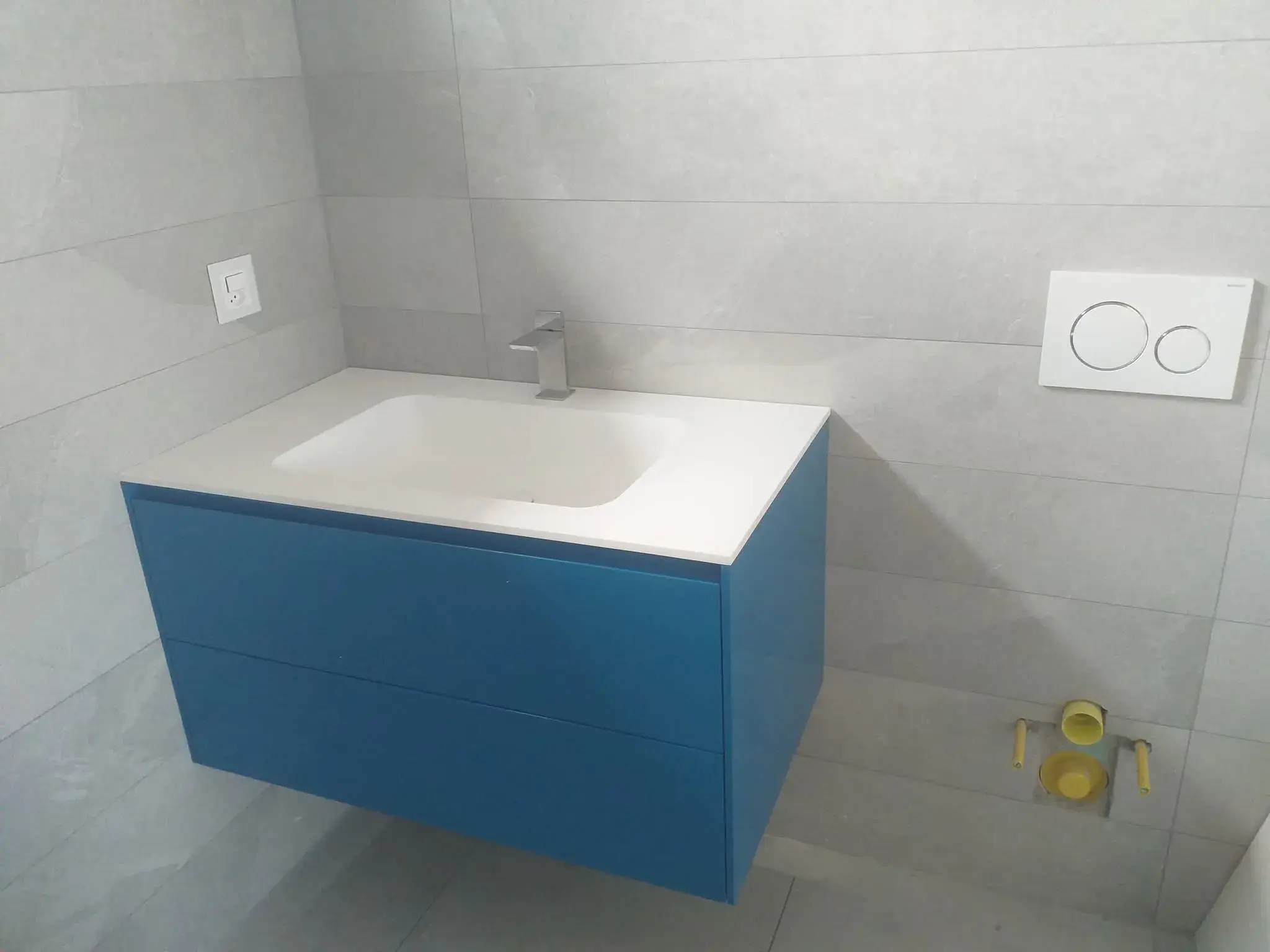 Vasque suspendue bleue laquée, vue de face, salle de bain bleue.