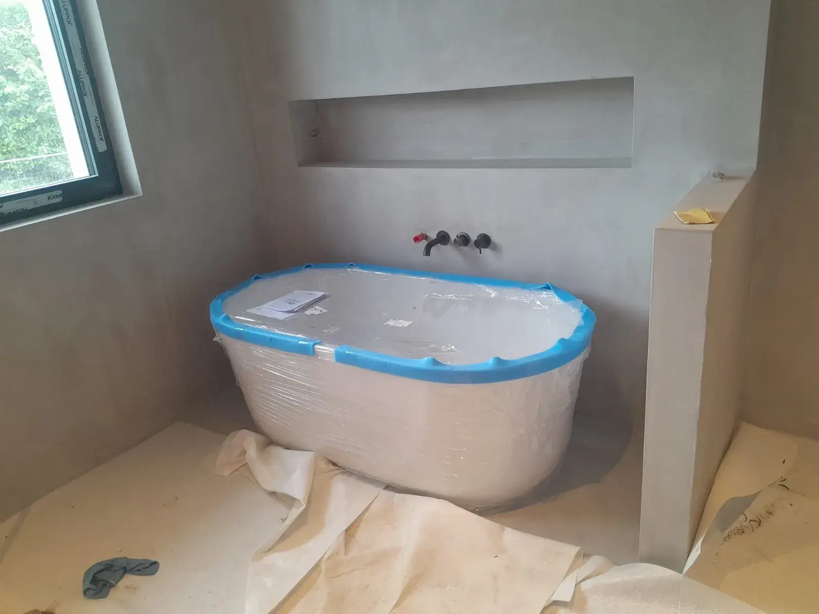 Baignoire îlot sous niche murale, mitigeur noir encastré, salle de bain design.