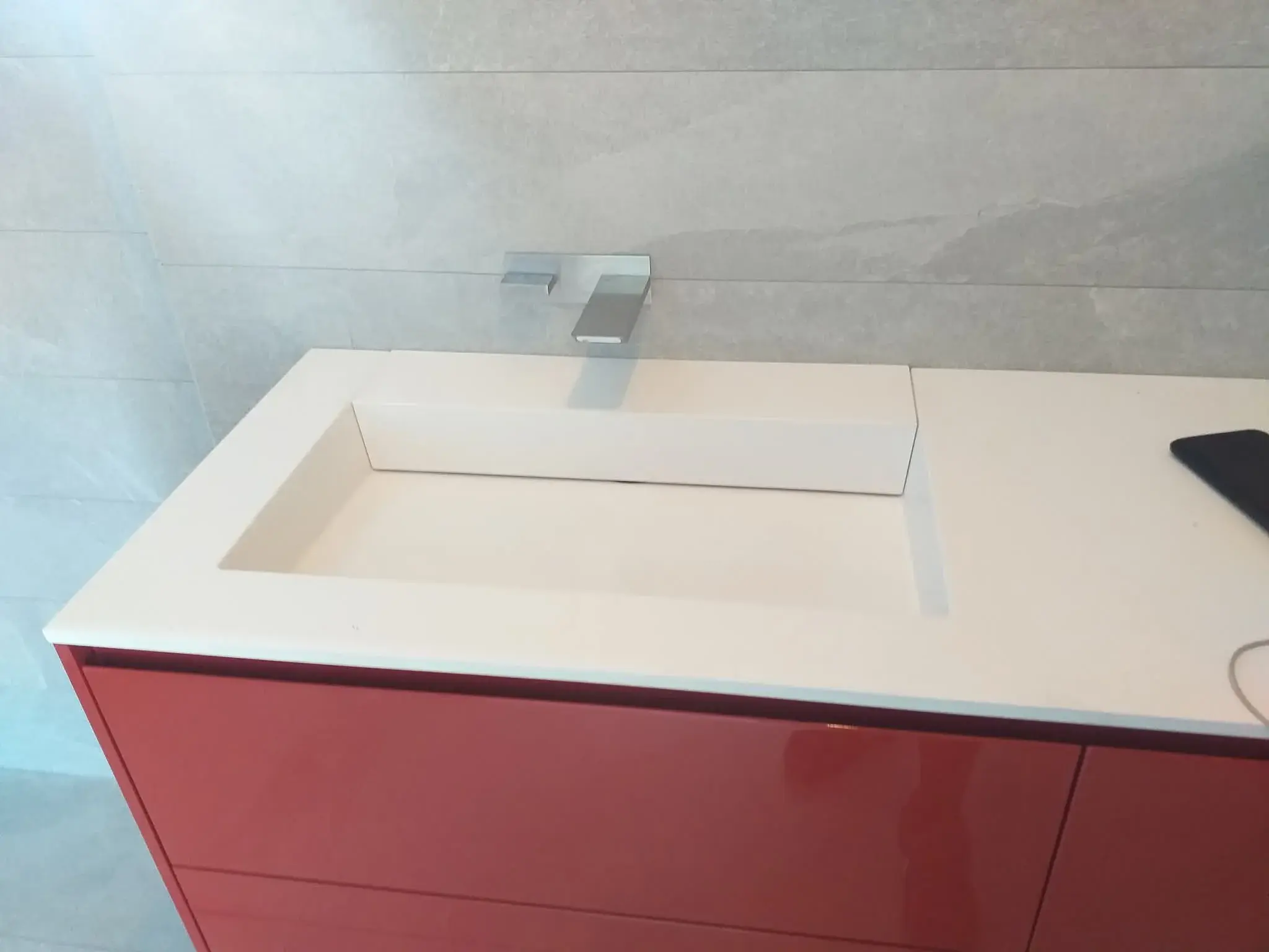 Détail de la vasque suspendue rouge laquée avec mitigeur chromé, salle de bain rouge.