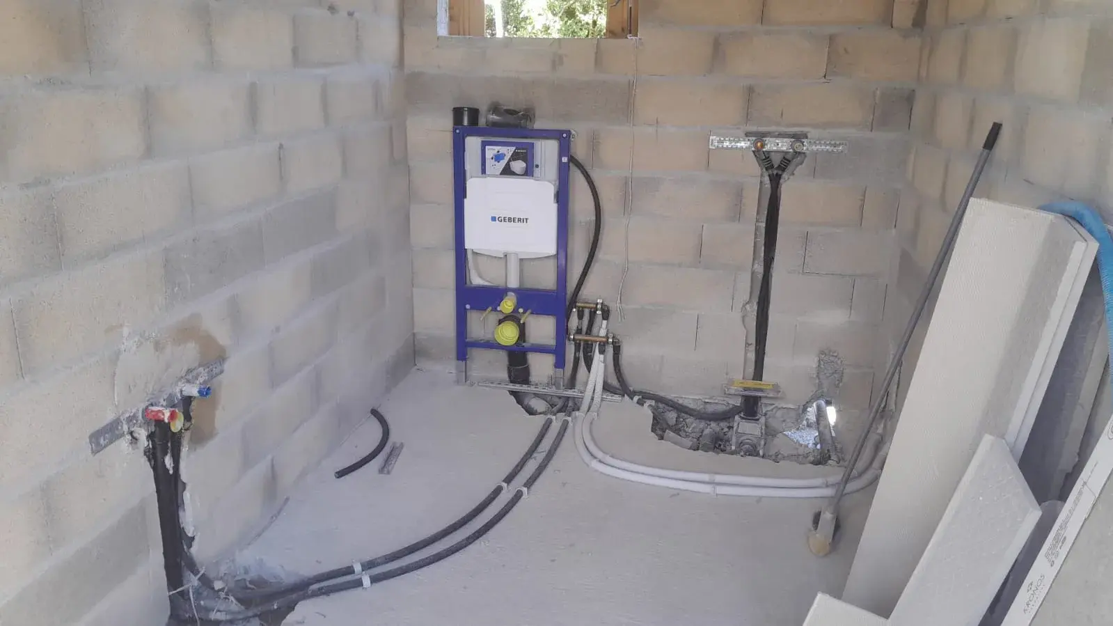 Avant fermeture des murs : cloisons brutes, cuvette Geberit encastrée et évacuations en attente, futur emplacement de la salle de bain béton brut.