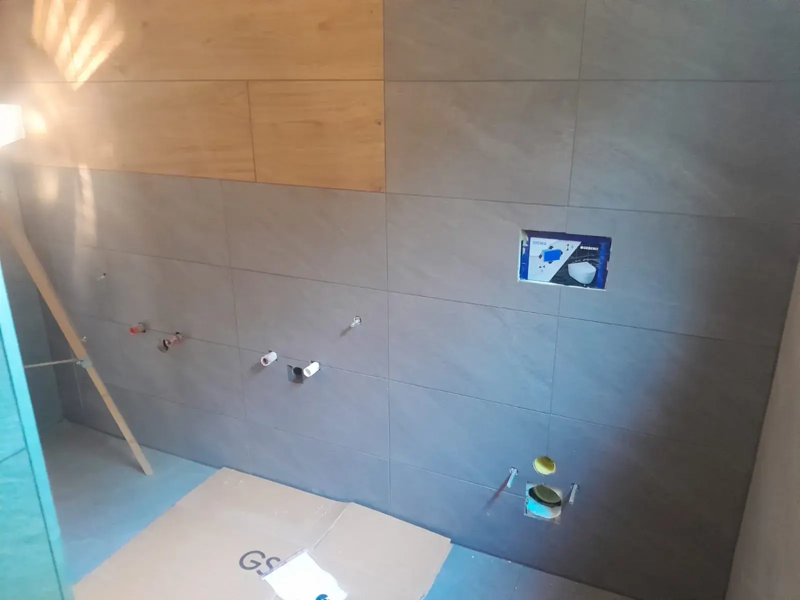 Avant fermeture : cuvette Geberit encore emballée dans sa niche, attentes de plomberie repérées.