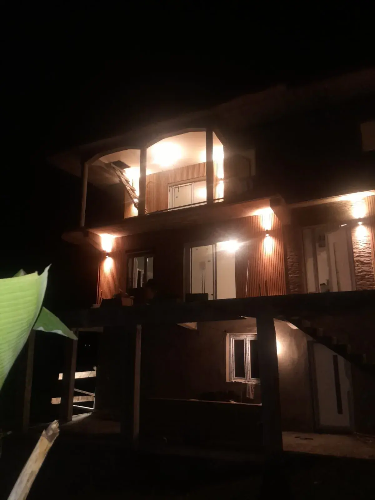 Façade de nuit, bardage bois éclairé par les luminaires extérieurs.