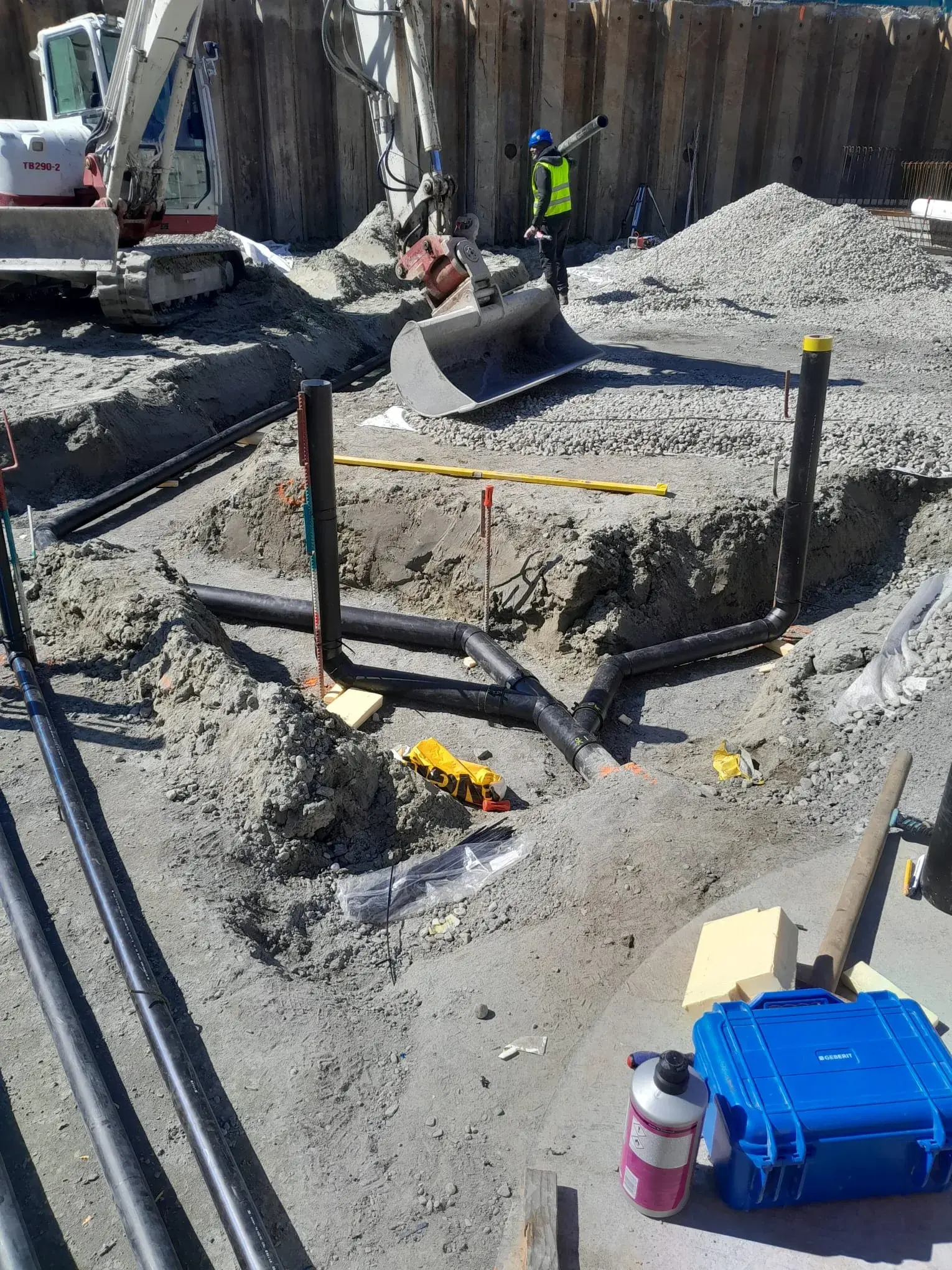 Terrassement à la mini-pelle pour la pose des réseaux enterrés, ouvrier posant une canalisation.