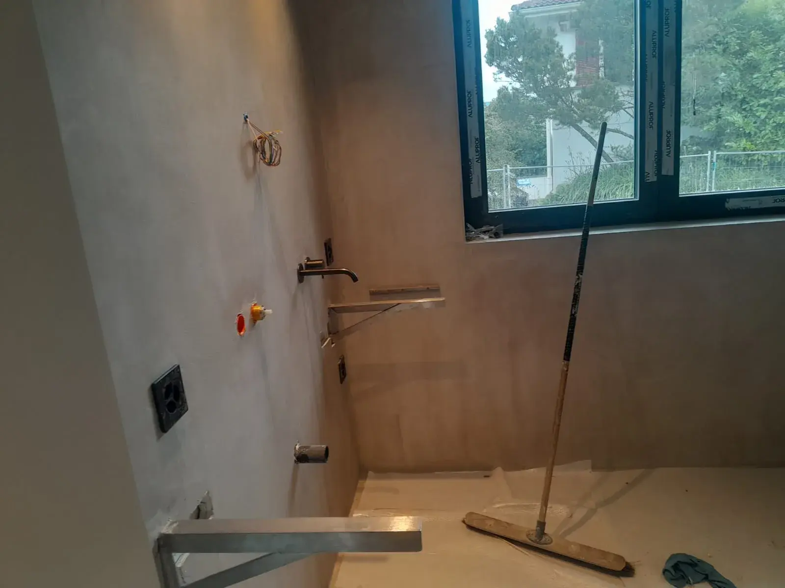 Arrivée d’eau et mitigeur posé avant carrelage, murs en enduit brut.