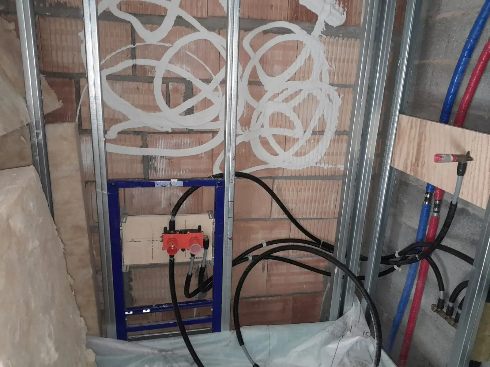 Cuvette Geberit encastrée contre un mur en brique, gaines d’alimentation repérées.